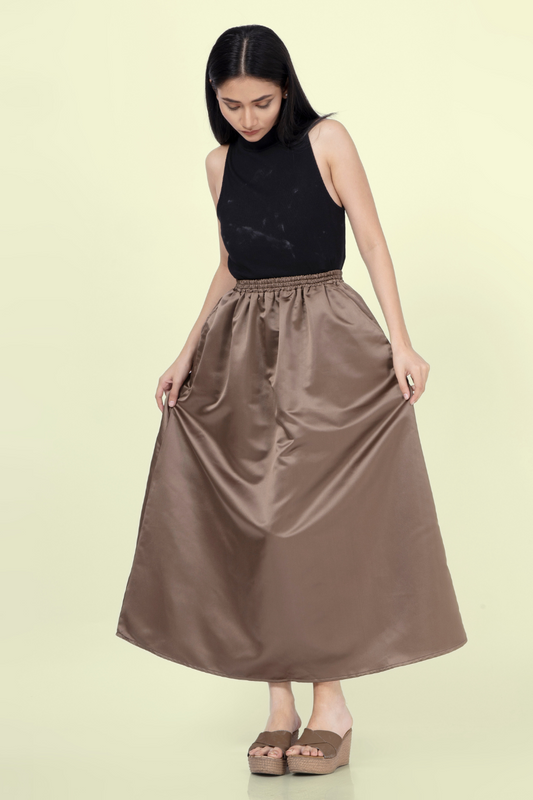 Model wearing a brown gathered skirt made from the 'Zinnia' sewing pattern. Features an elastic waistband and flowing silhouette for a classic look.