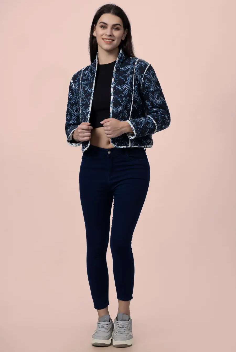 Model wearing the Romy reversible quilted jacket in a dark blue geometric pattern. A stylish and warm outerwear piece with contrast binding.