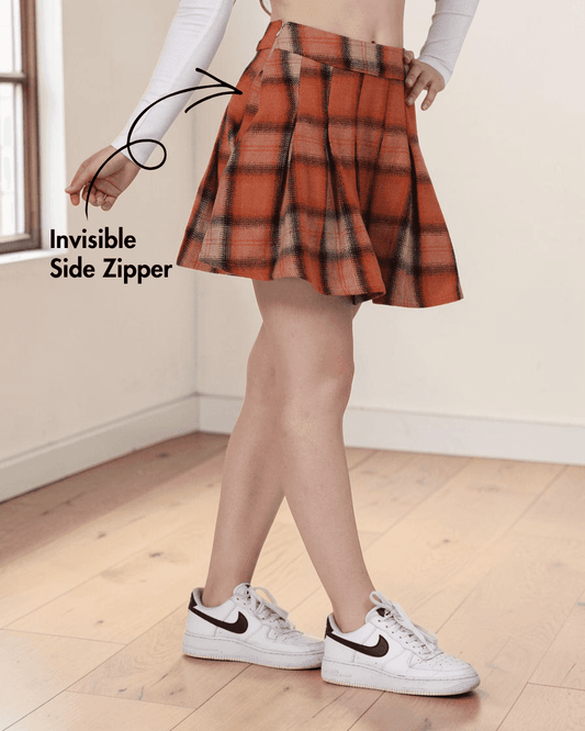 Close-up of a pleated mini skirt with side zipper, worn by a model with hand on hip