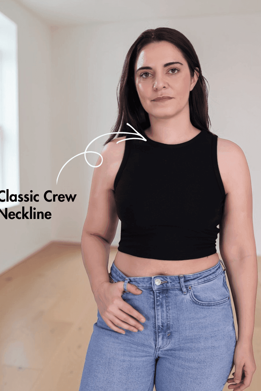 Woman wearing black sleeveless crop tank top with classic crew neckline and high-waisted jeans