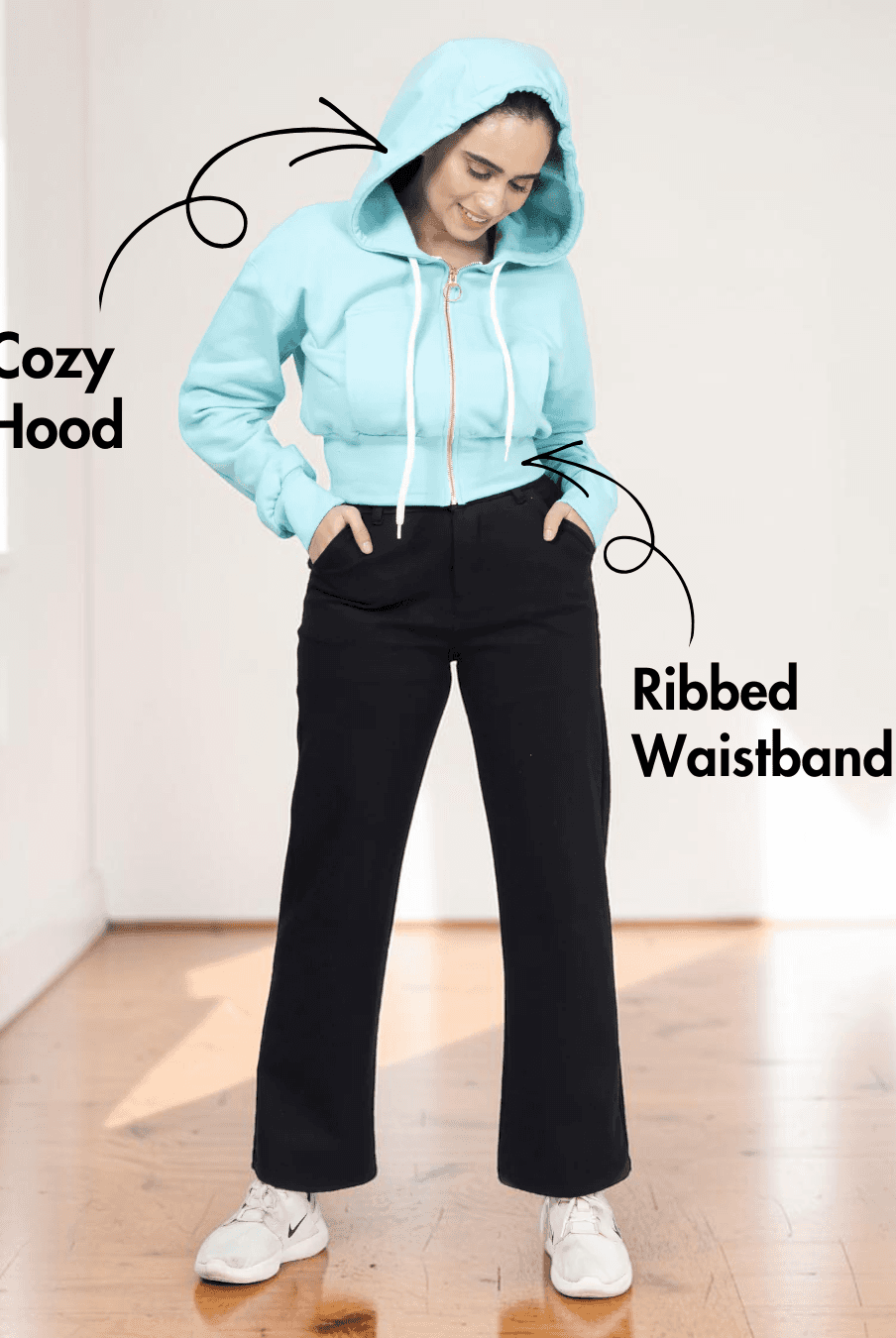 Woman in gray hoodie with ribbed waistband and drawstrings, showing the sewing pattern for a stylish hooded sweatshirt