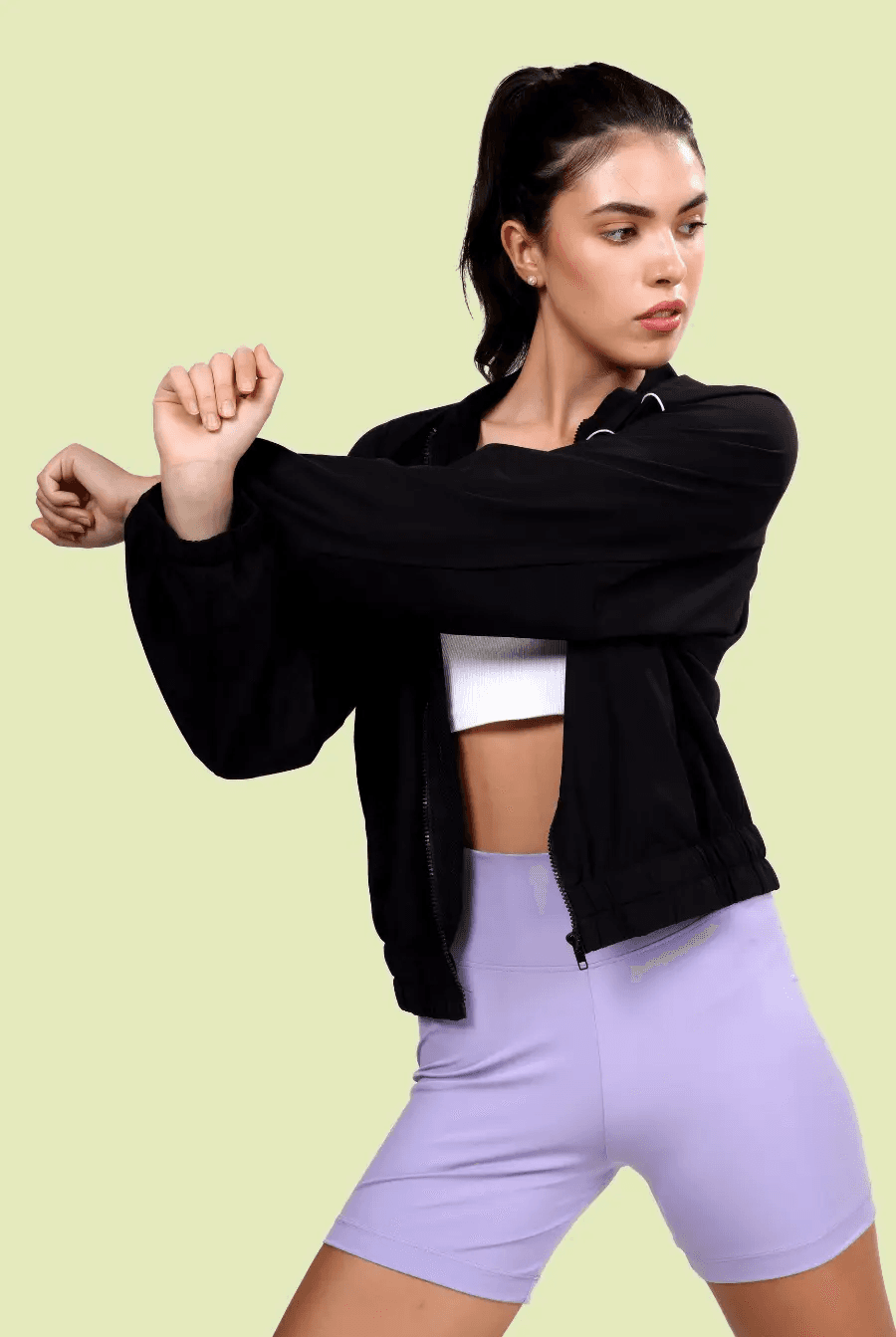 Stretching in the Naomi windbreaker, showcasing its comfortable fit and elastic cuffs. A stylish and functional outerwear piece for active and casual wear.