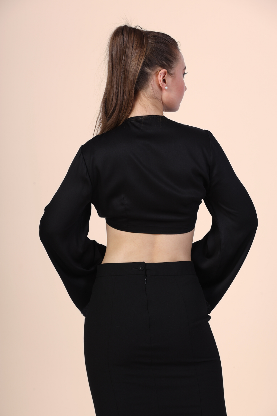 Back Pose Image of a model wearing a tie front crop top sewed with winslet's patterns paired with black midi skirt