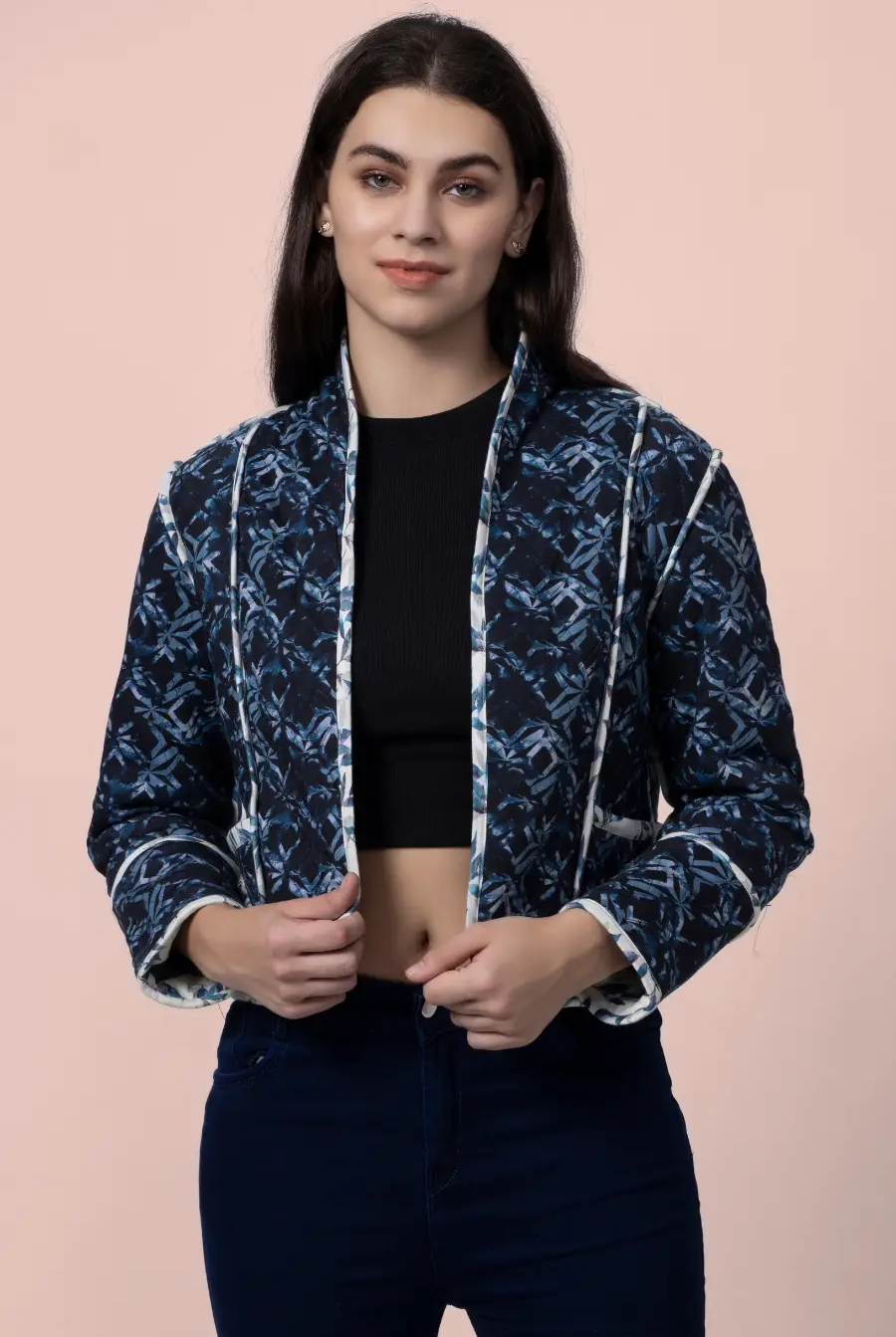 Model adjusting the Romy reversible quilted jacket in a dark blue geometric pattern. A stylish, lightweight outerwear piece with contrast binding.