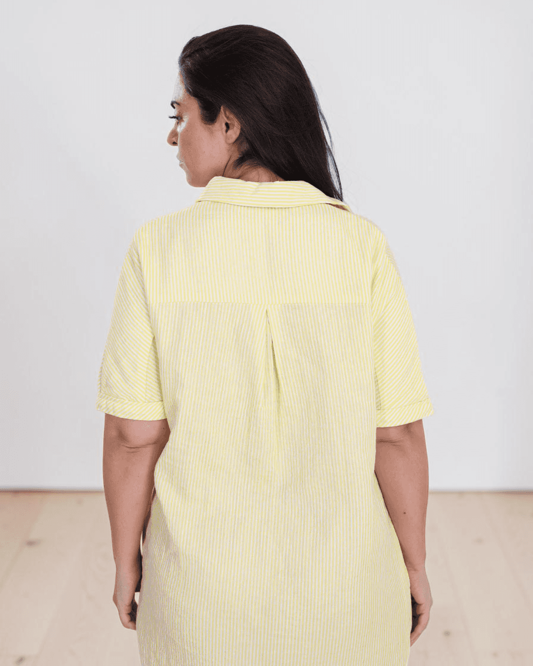 Yellowe linen shirt dress with traditional collar, button-down front, and side pockets, back view