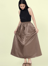 Model wearing a brown gathered skirt made from the 'Zinnia' sewing pattern. Features an elastic waistband and flowing silhouette for a classic look.