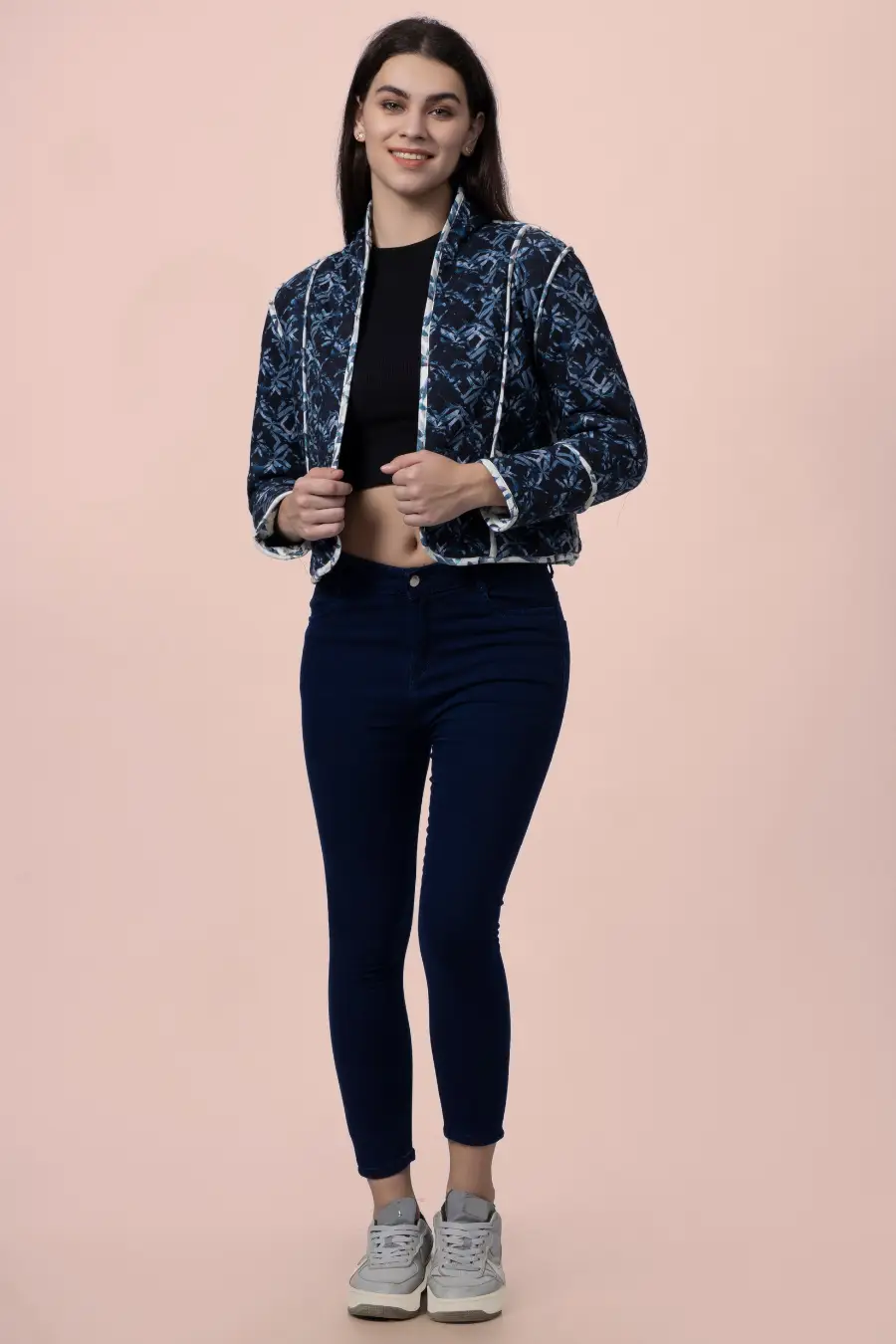 Model wearing the Romy reversible quilted jacket in a dark blue geometric pattern. A stylish and warm outerwear piece with contrast binding.