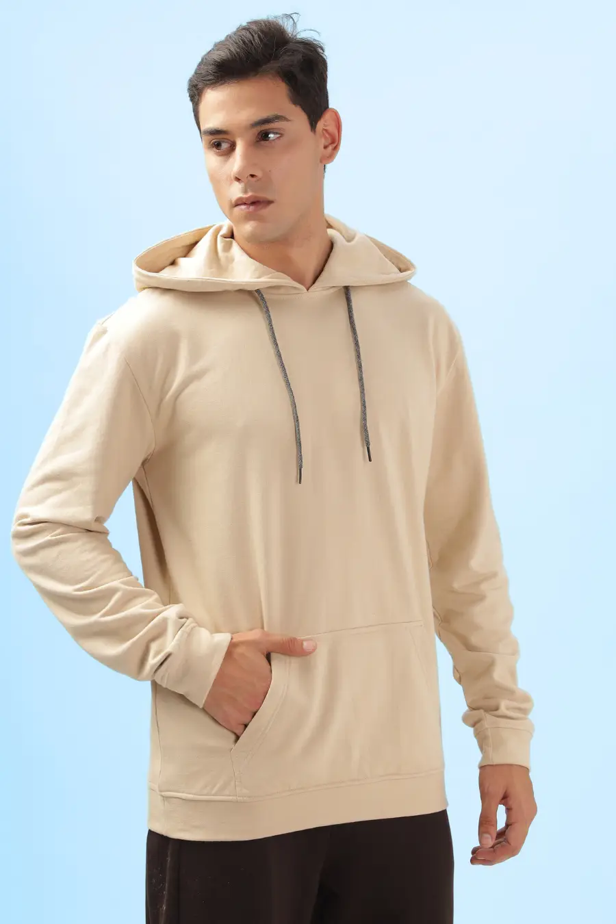 Side view of a beige men's hoodie from the 'Atlas' sewing pattern. Showcases a comfortable fit with a front pocket and ribbed cuffs for a casual look.