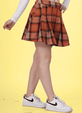 Woman wearing a box pleat skirt with a white off-shoulder top and sneakers