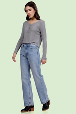 Full-body view of a model wearing the Riley long sleeve Henley top. Styled casually with jeans and boots for a modern look.