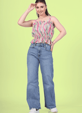 Woman wearing a strappy ruffle top with blue jeans