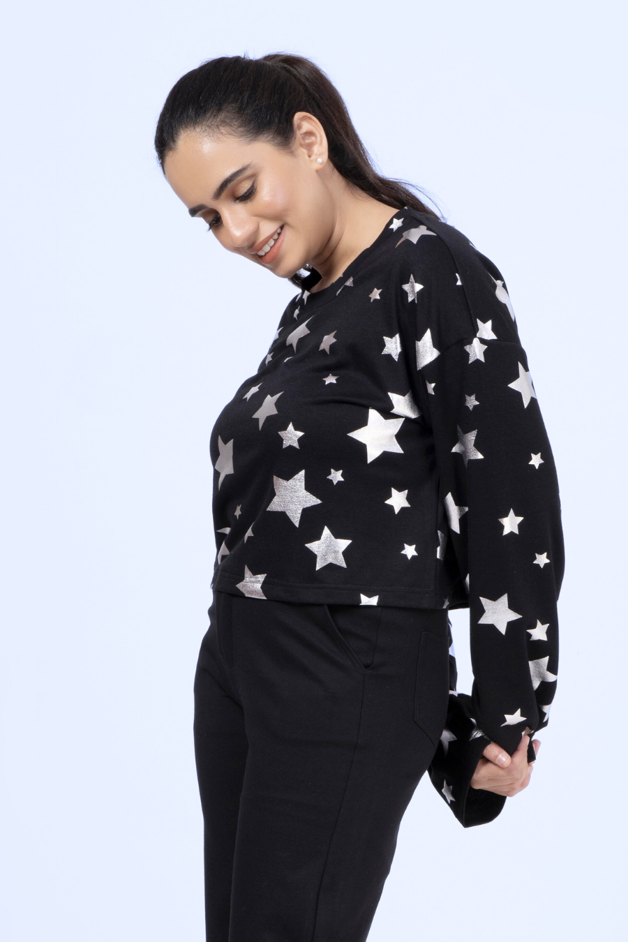 Side view of the Selena sweatshirt in black with silver stars, highlighting the round neck, drop shoulders, and comfortable fit.