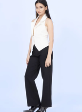 Side view of a model wearing a white halter neck vest with a sharp collar and tailored fit. The vest cinches at the waist, creating a flattering silhouette.