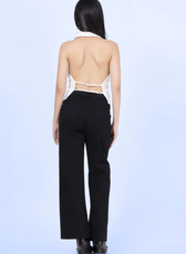 Back view of a model wearing a backless halter neck vest with adjustable straps. The design highlights an open-back style for a bold fashion statement.