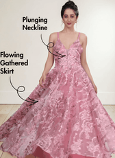 Model wearing pink floral lace evening gown with plunging neckline, flowing gathered skirt, delicate straps, low scoop back