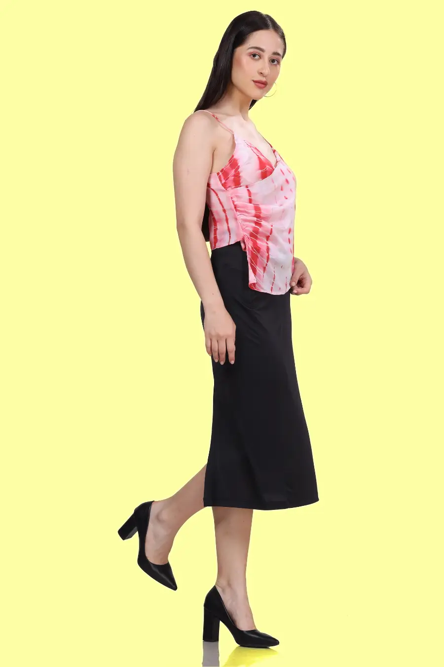 Side view of a model wearing a strappy top with thin straps highlighting pleat details and flattering drapes 