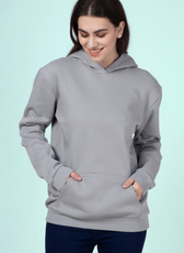 Woman wearing a gray hoodie with hands in the kangaroo pocket, showcasing the comfortable and casual design of the 'Rhea' sewing pattern.