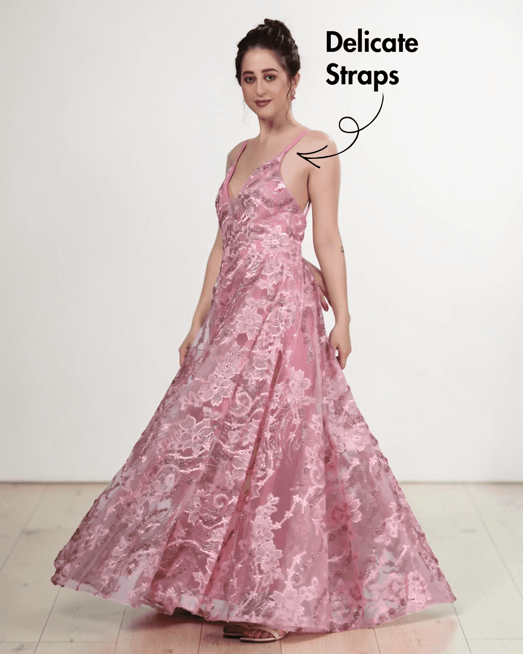 Model wearing pink floral lace evening gown with plunging neckline, flowing gathered skirt, delicate straps, low scoop back, side view