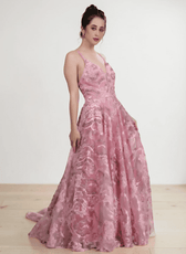 Model wearing pink floral lace evening gown with plunging neckline, flowing gathered skirt, delicate straps, low scoop back, side view