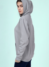 Side view of a woman wearing a gray hoodie, displaying the relaxed fit and clean finish of the 'Rhea' sewing pattern.