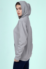 Side view of a woman wearing a gray hoodie, displaying the relaxed fit and clean finish of the 'Rhea' sewing pattern.