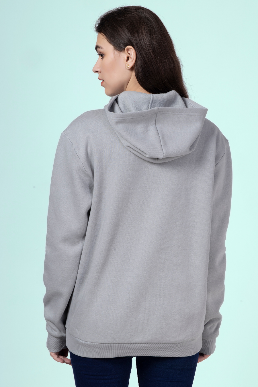 Back view of a woman wearing a gray hoodie, showcasing the hood and structured ribbed hem of the 'Rhea' sewing pattern.