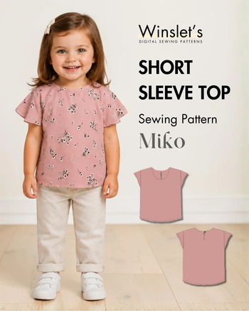 Young girl wearing a pink floral short sleeve top with a classic round neckline, cap sleeves, and back buttoned loop closure, standing indoors