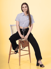 a woman wearing a cropped blouse sitting on a chait. blouse is design with the cedar cropped blouse sewing pattern by winslets