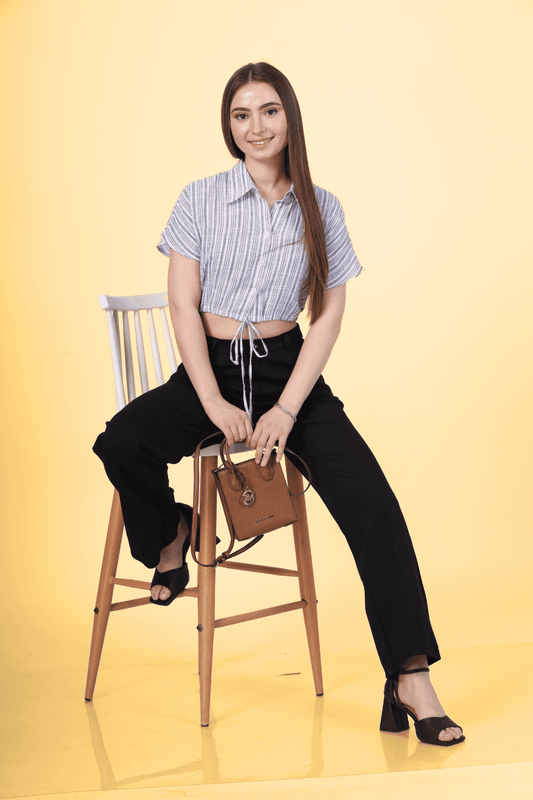 a woman wearing a cropped blouse sitting on a chait. blouse is design with the cedar cropped blouse sewing pattern by winslets