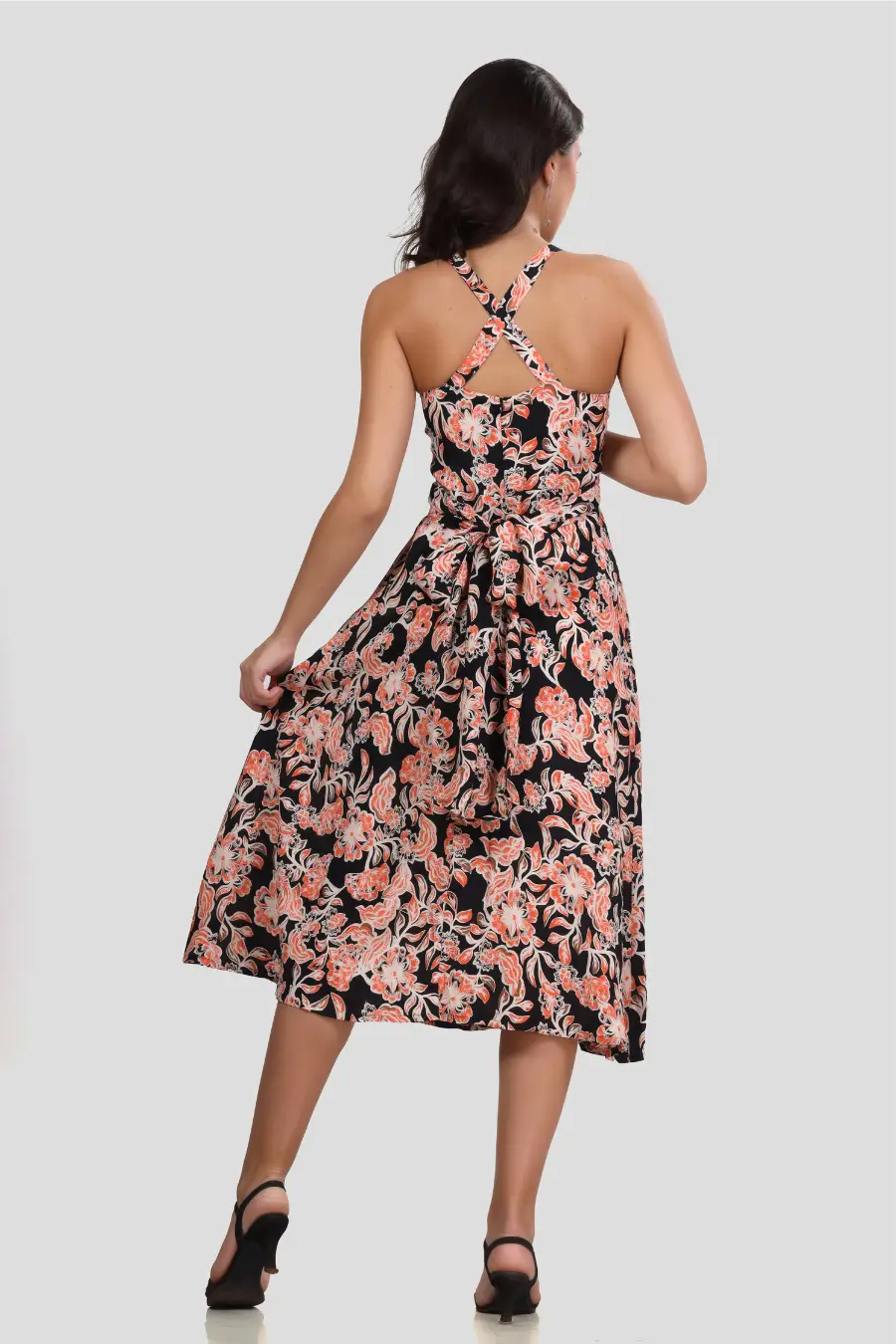 Back view of the 'Camellia' wrap dress highlighting the cross-back straps and waist tie. The flared skirt provides a feminine silhouette.