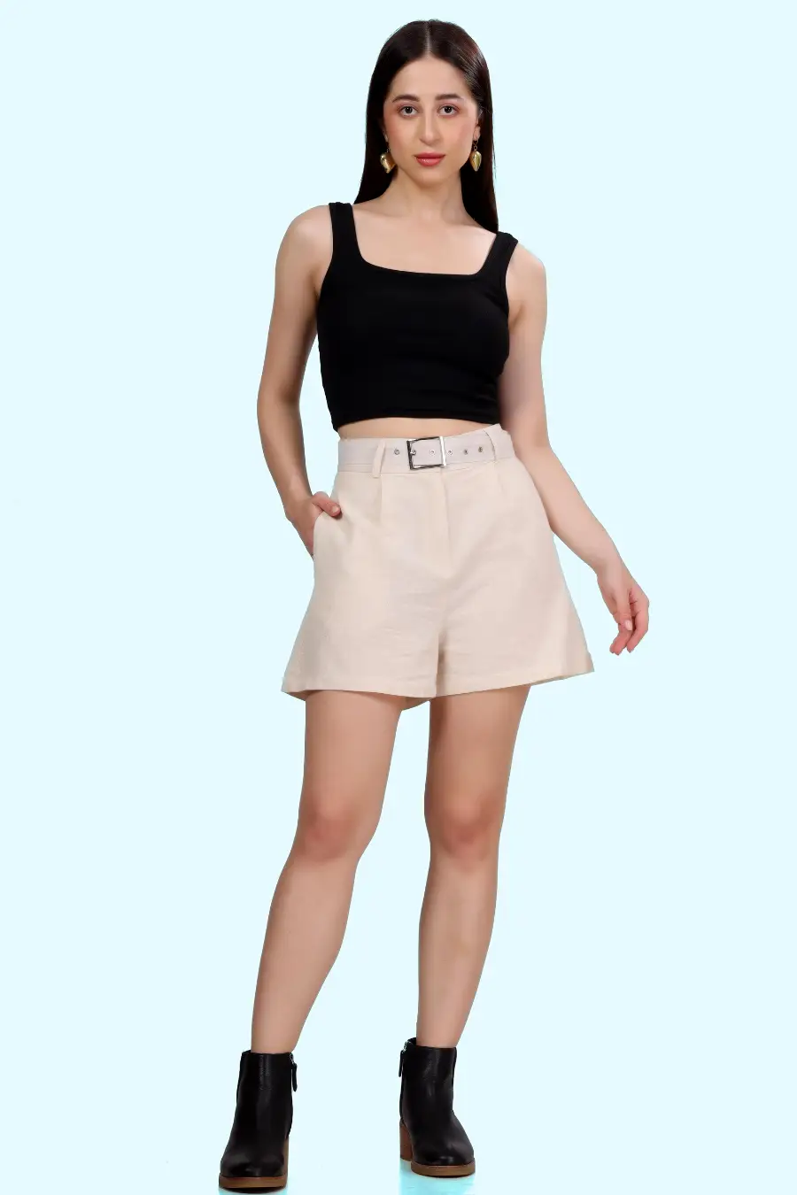 Front view of model wearing high-waisted shorts with coordinating belt and pleat details, paired with a black top.