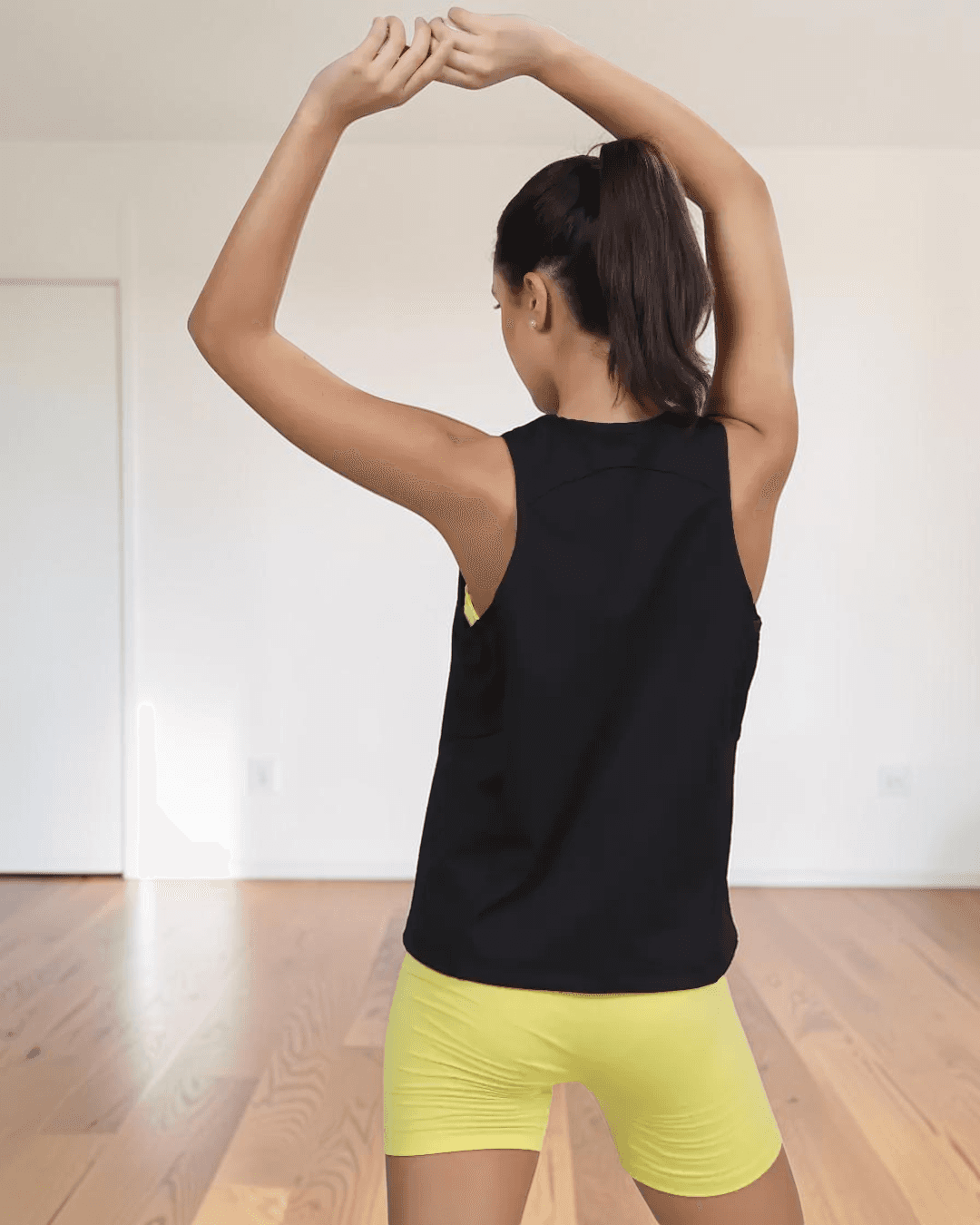 Back View of model in black sleeveless tank top with high neckline, highlighting pattern details and relaxed fit of 'Tracy' sewing pattern