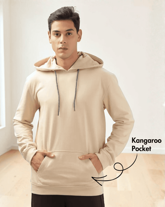 Model wearing beige hoodie sewing pattern with kangaroo pocket and ribbed cuffs