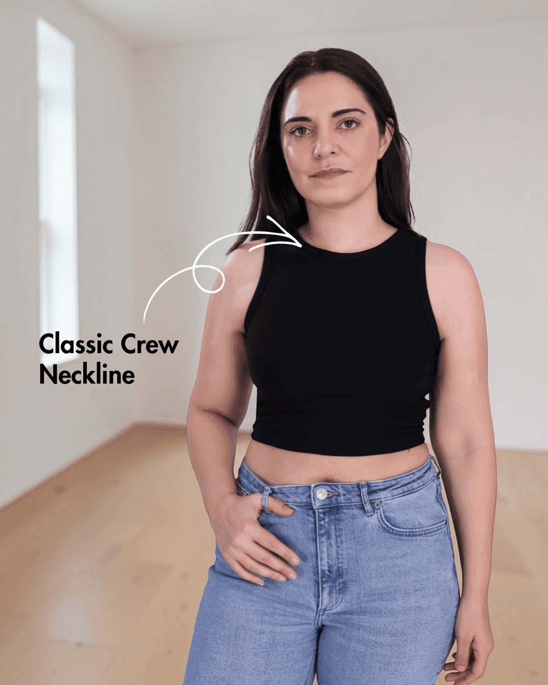 Woman wearing black sleeveless crop tank top with classic crew neckline and high-waisted jeans