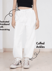 Close-up of white joggers with elastic waistband and cuffed ankles, showcasing sewing pattern details