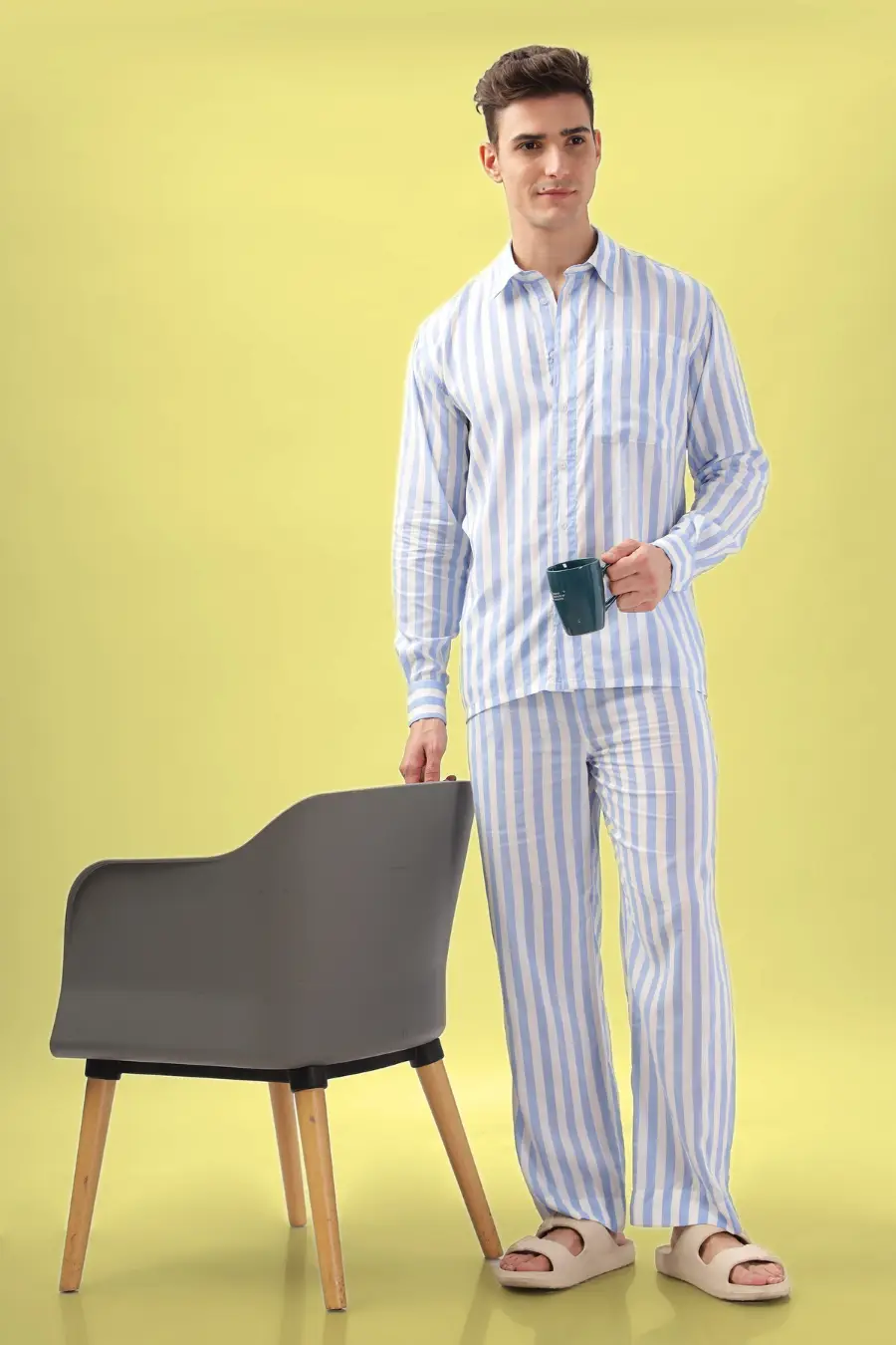 Model holding a coffee mug while wearing the 'Arbor' men's pajama set. A relaxed loungewear sewing pattern with a long-sleeve shirt and matching pants.