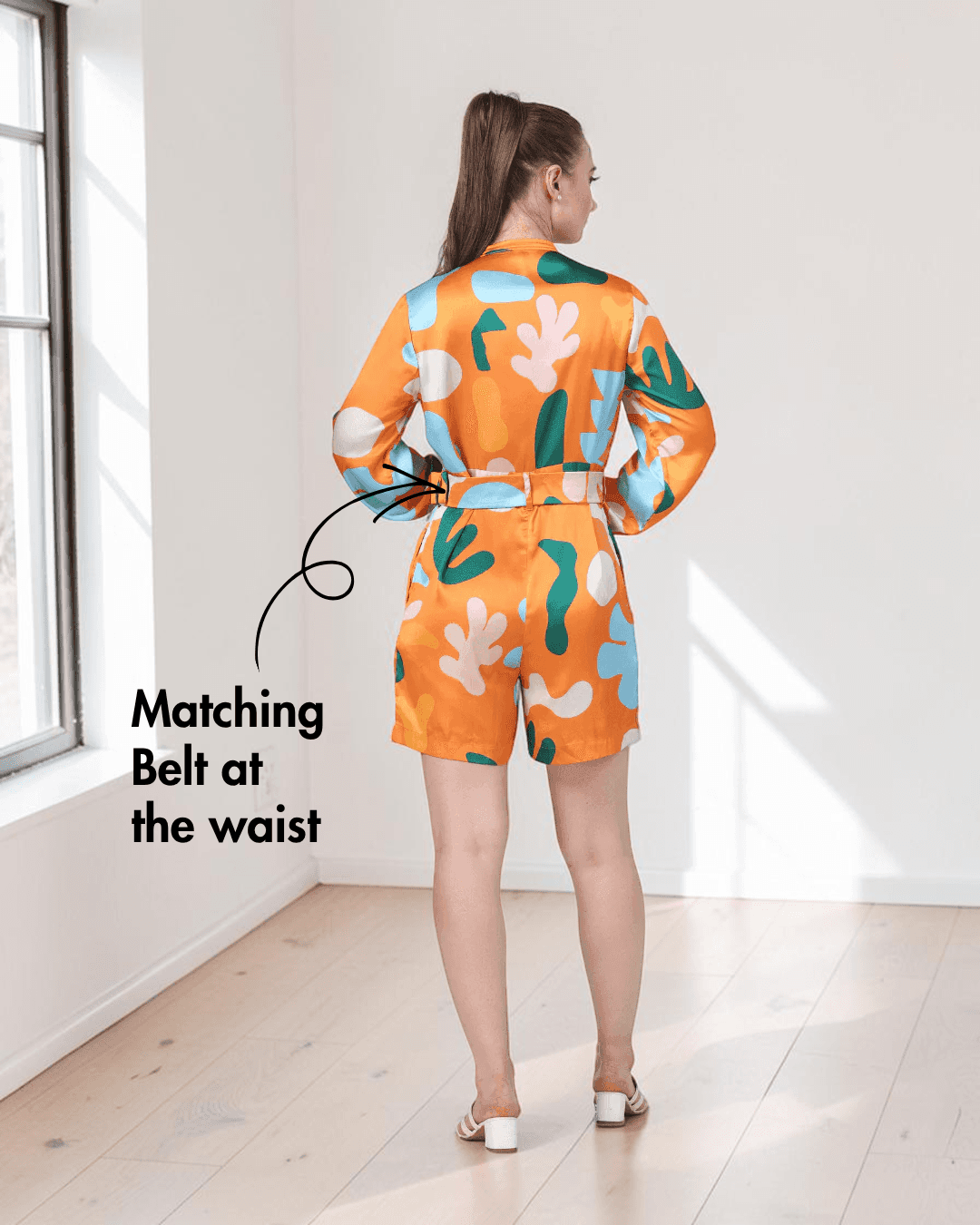 Model wearing floral playsuit with matching belt and long sleeves, back view