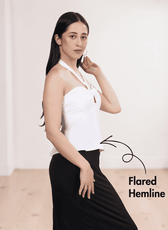Side view of white halter top with smocked back panel, model in black skirt