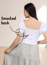 Back view of white puff sleeve top with smocked back panel and floral skirt