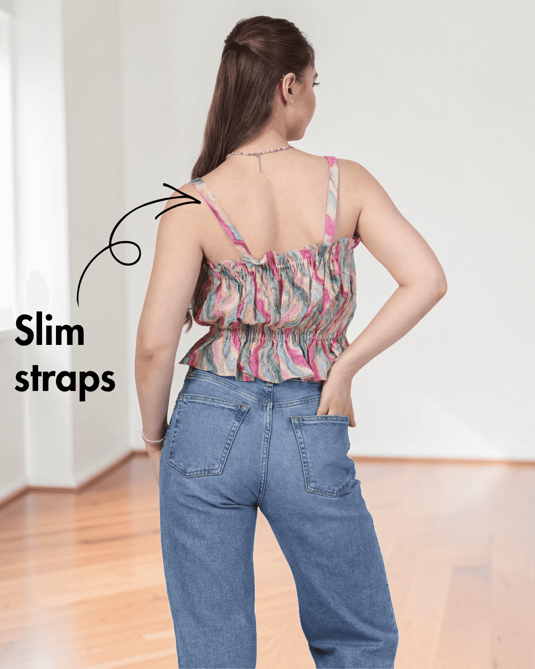 Back view of woman in pink ruffle top with slim straps and elastic waist