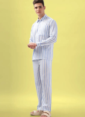 Model wearing a striped men's pajama set made using the 'Arbor' sewing pattern. Long-sleeve button-up shirt and relaxed-fit pants, perfect for loungewear.