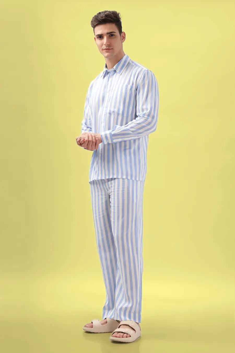 Model wearing a striped men's pajama set made using the 'Arbor' sewing pattern. Long-sleeve button-up shirt and relaxed-fit pants, perfect for loungewear.