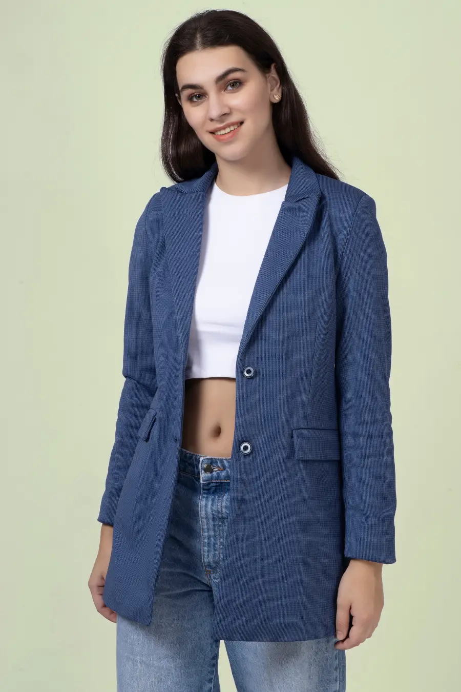 Model wearing a blue straight-cut coat made using the 'Camille' sewing pattern. The design includes a notched lapel, single-breasted closure, and flap pockets.