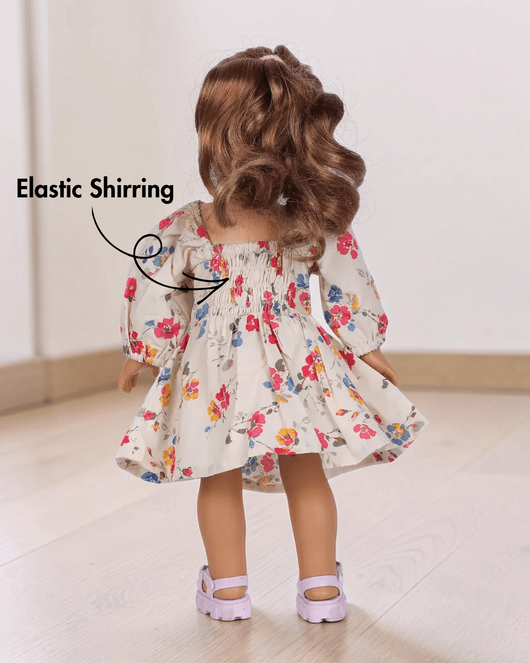 Back view of doll Millie in floral dress with elastic shirring and puff sleeves