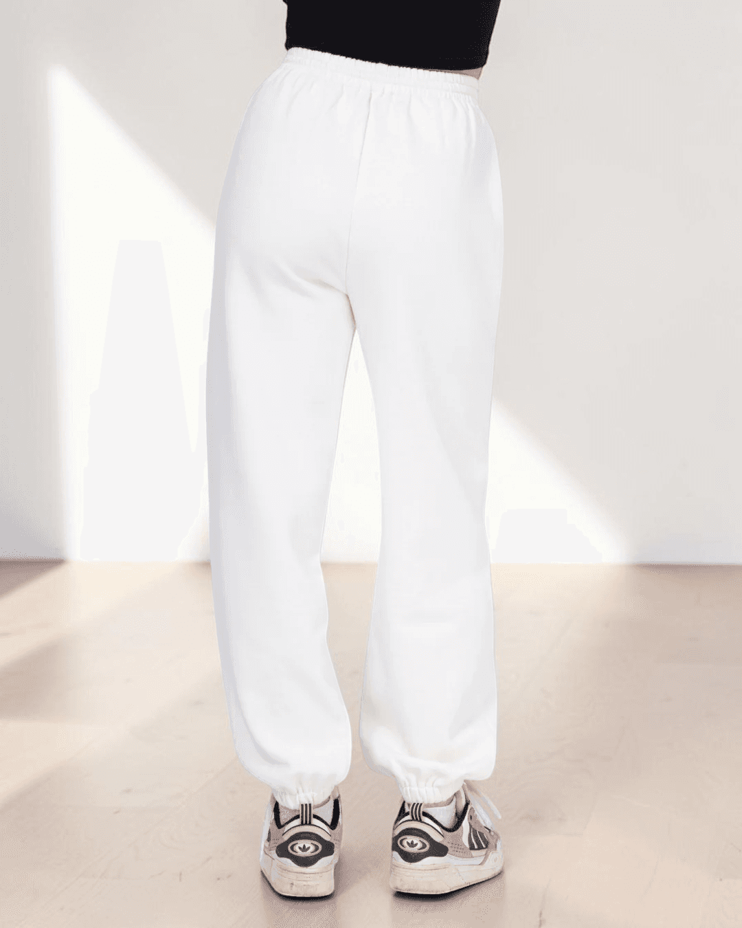 Model wearing white joggers sewing pattern with elastic waistband and cuffed ankles, demonstrating pattern fit and style, back view