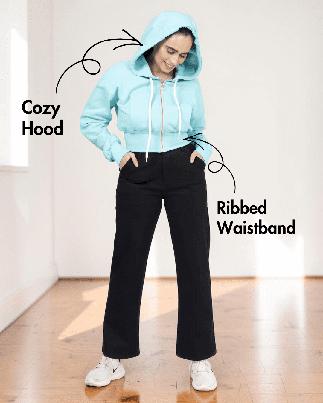 Woman in gray hoodie with ribbed waistband and drawstrings, showing the sewing pattern for a stylish hooded sweatshirt