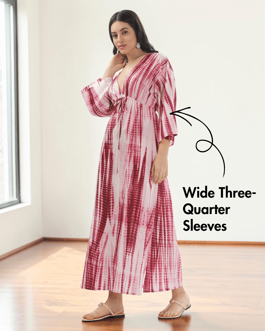 Model wearing pink and red tie-dye kaftan dress with deep V-neckline and wide three-quarter sleeves