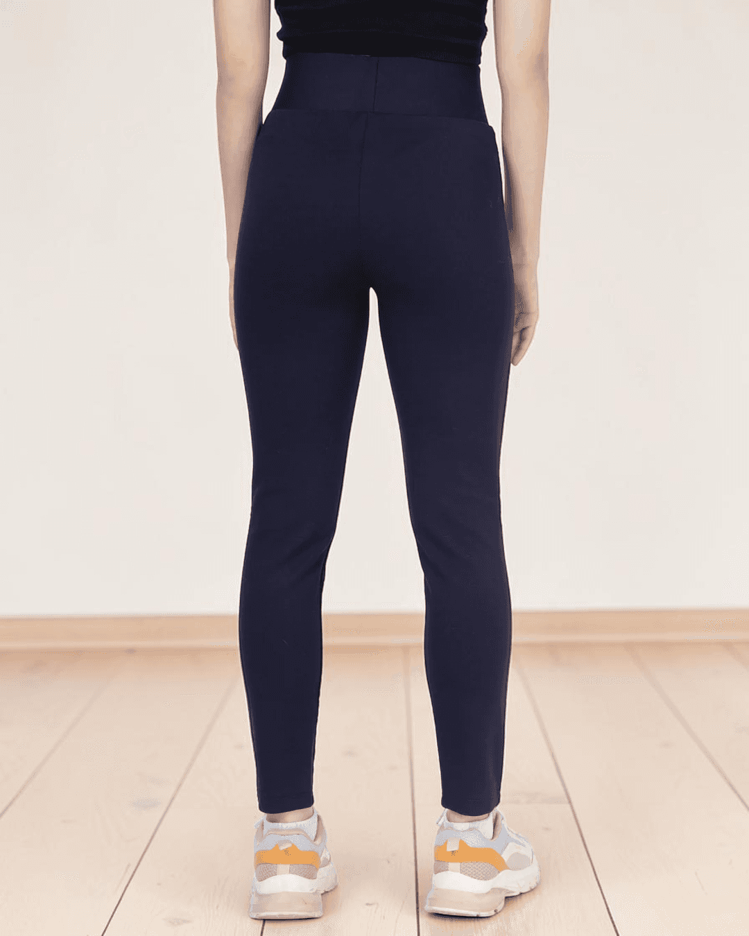Back view of woman in navy leggings sewing pattern highlighting high waist and fitted style