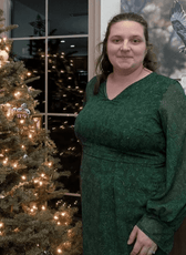 Woman in green dress near Christmas tree, showcasing celestia sheath dress sewing pattern