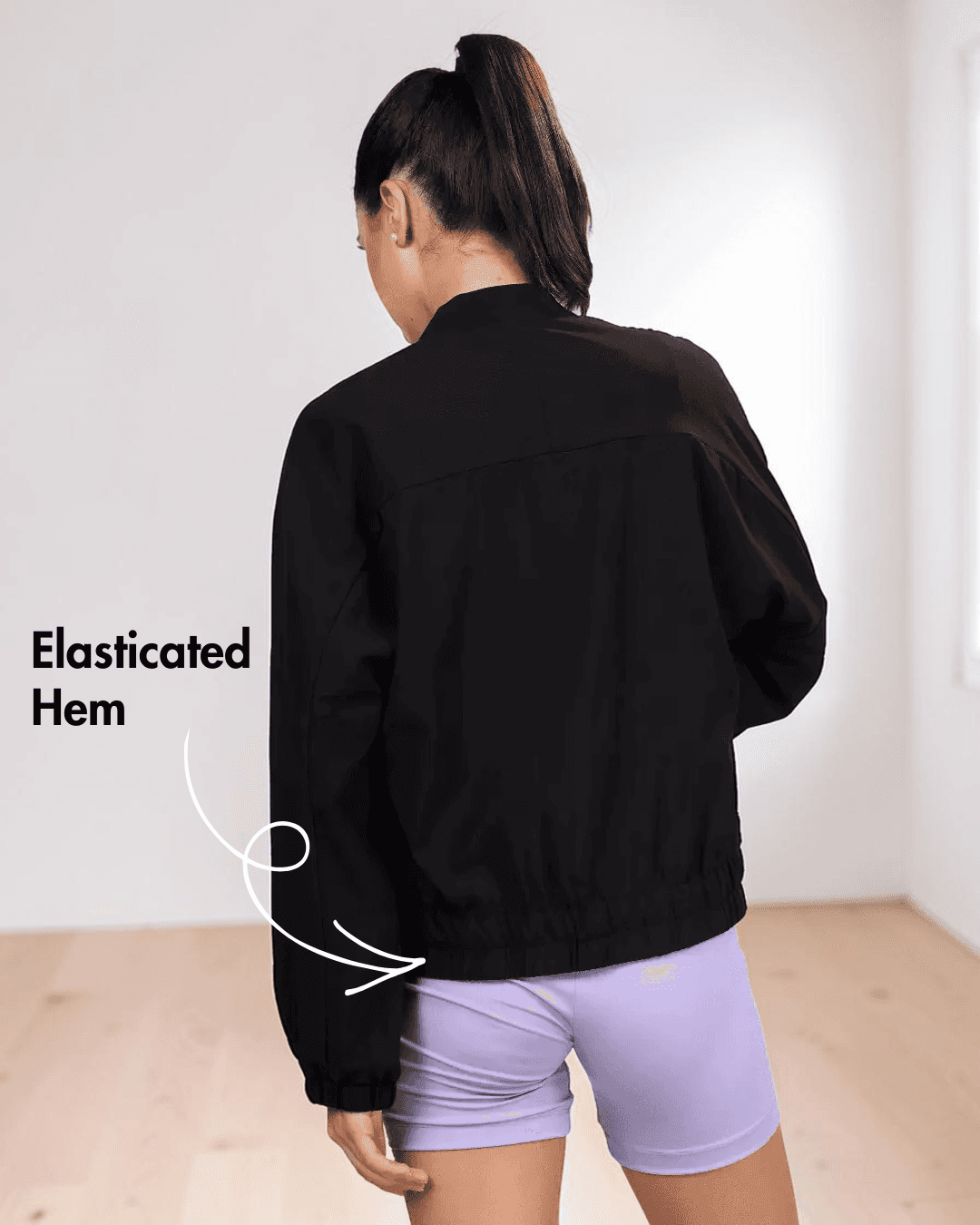 Back View of Model wearing women's windbreaker jacket Naomi with pattern details and purple shorts